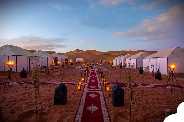 Luxury desert camps in Morocco with elegant Berber tents and golden Sahara dunes at sunset.