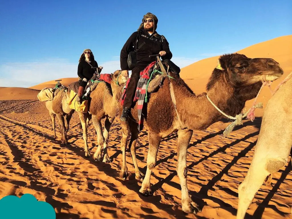 Traveler dressed in appropriate Morocco travel outfits during camel trek in Sahara Desert